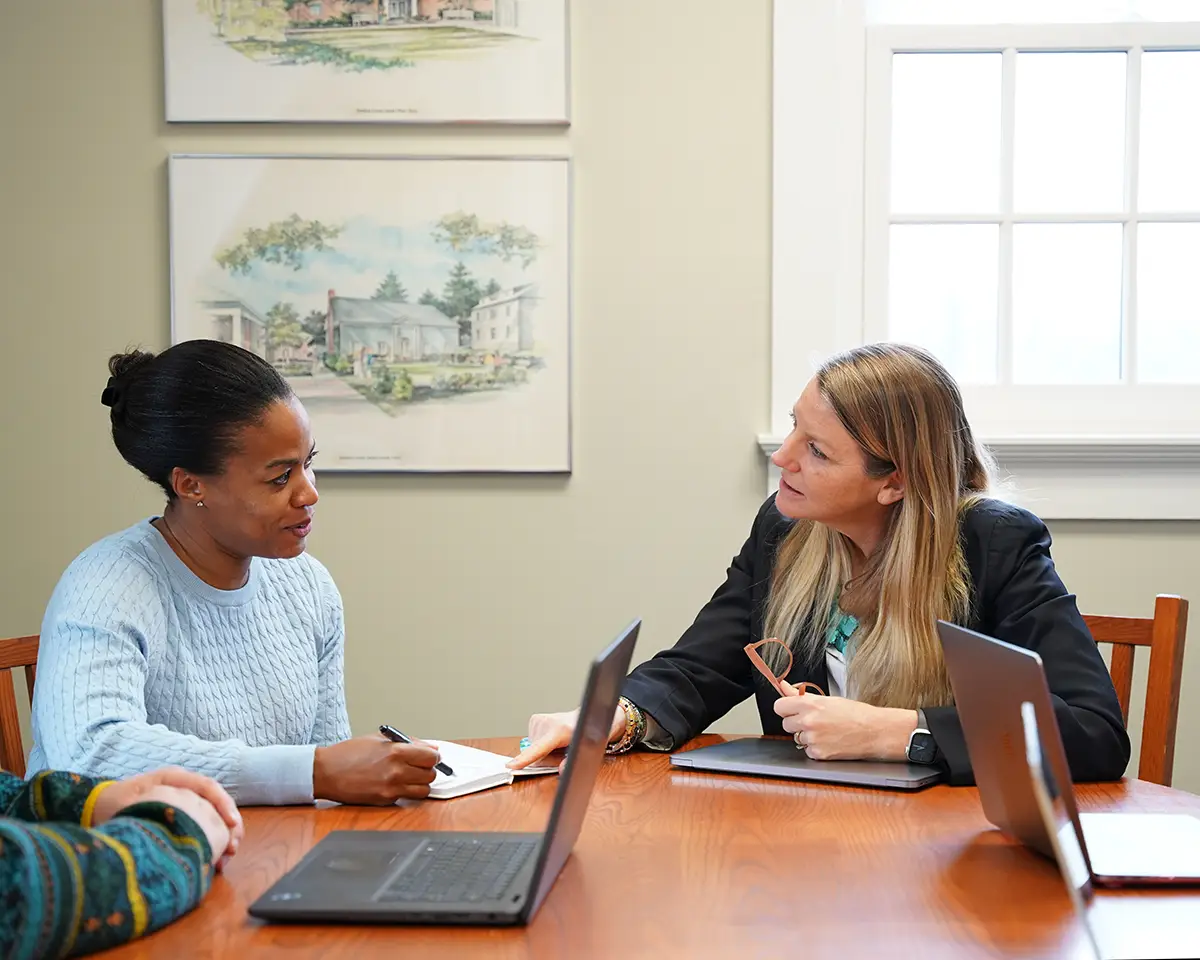 independent school consultant talking to a client one on one at table with laptop
