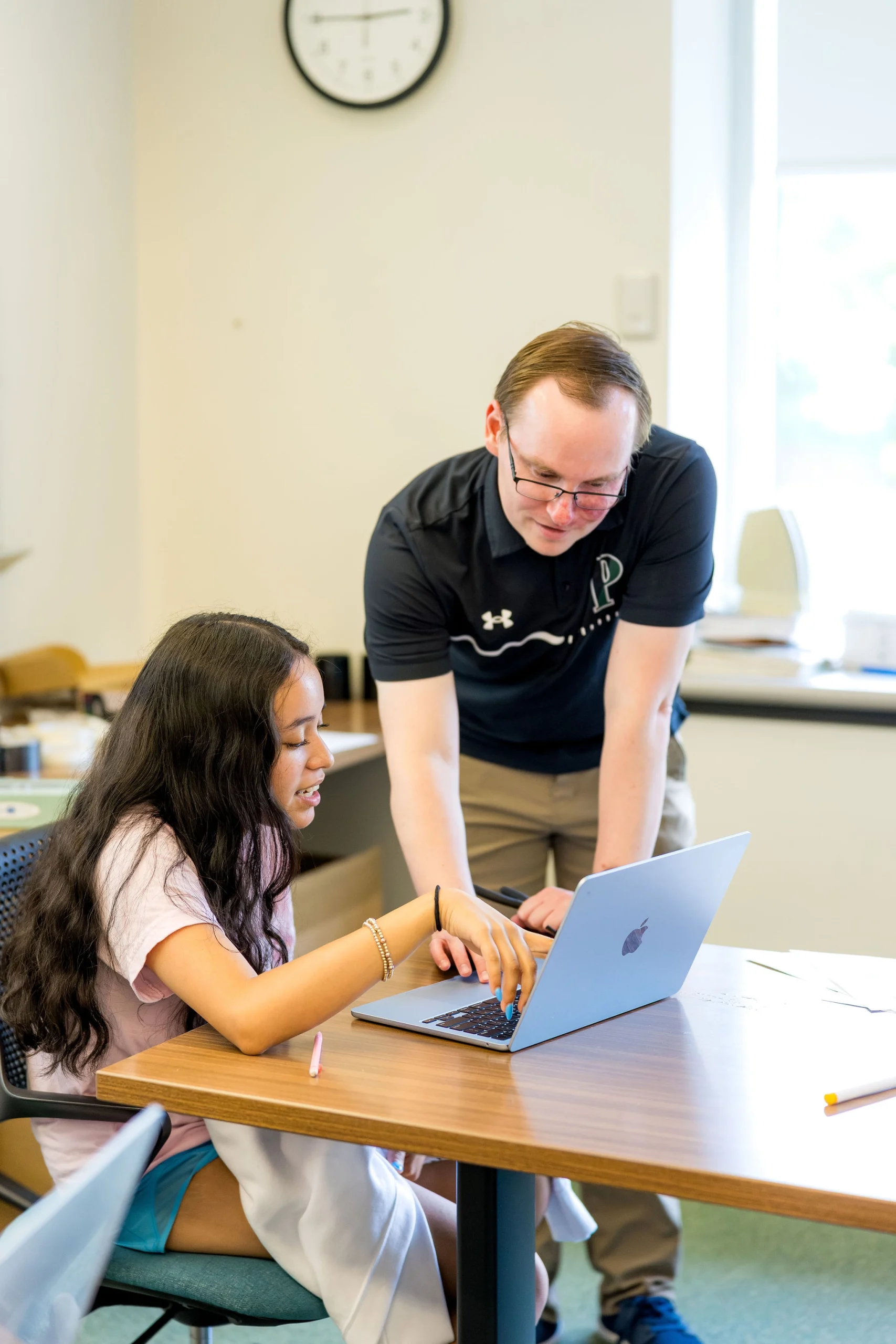 student and teacher discussing work on computer one on one in classroom
