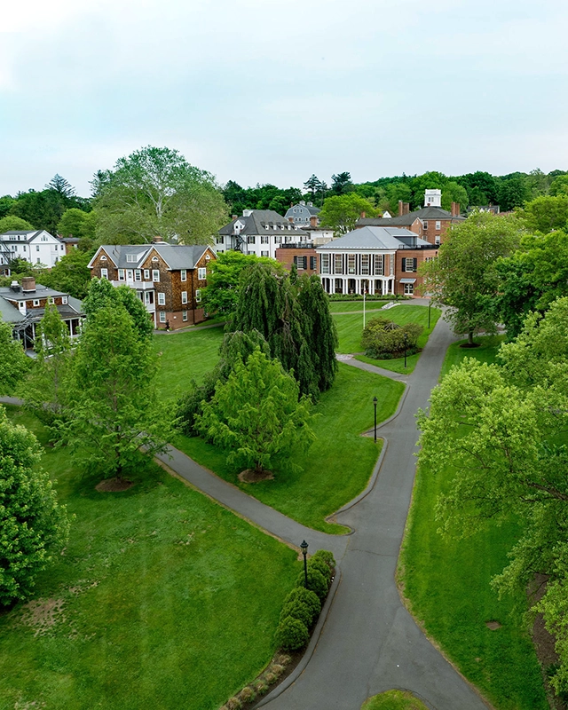 Aerial view of the Miss Porter's School campus with tree-lined paths, green lawns, and several large brick and white buildings surrounded by lush greenery.