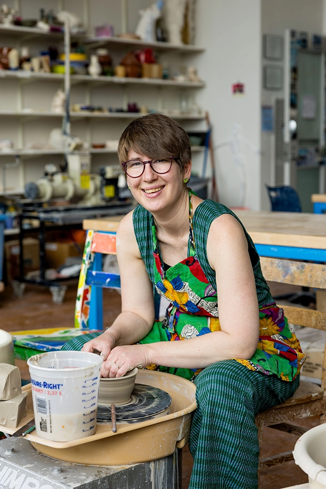 Ceramics teacher Ariana Kolins sits at a pottery wheel in the MPS ceramics studio