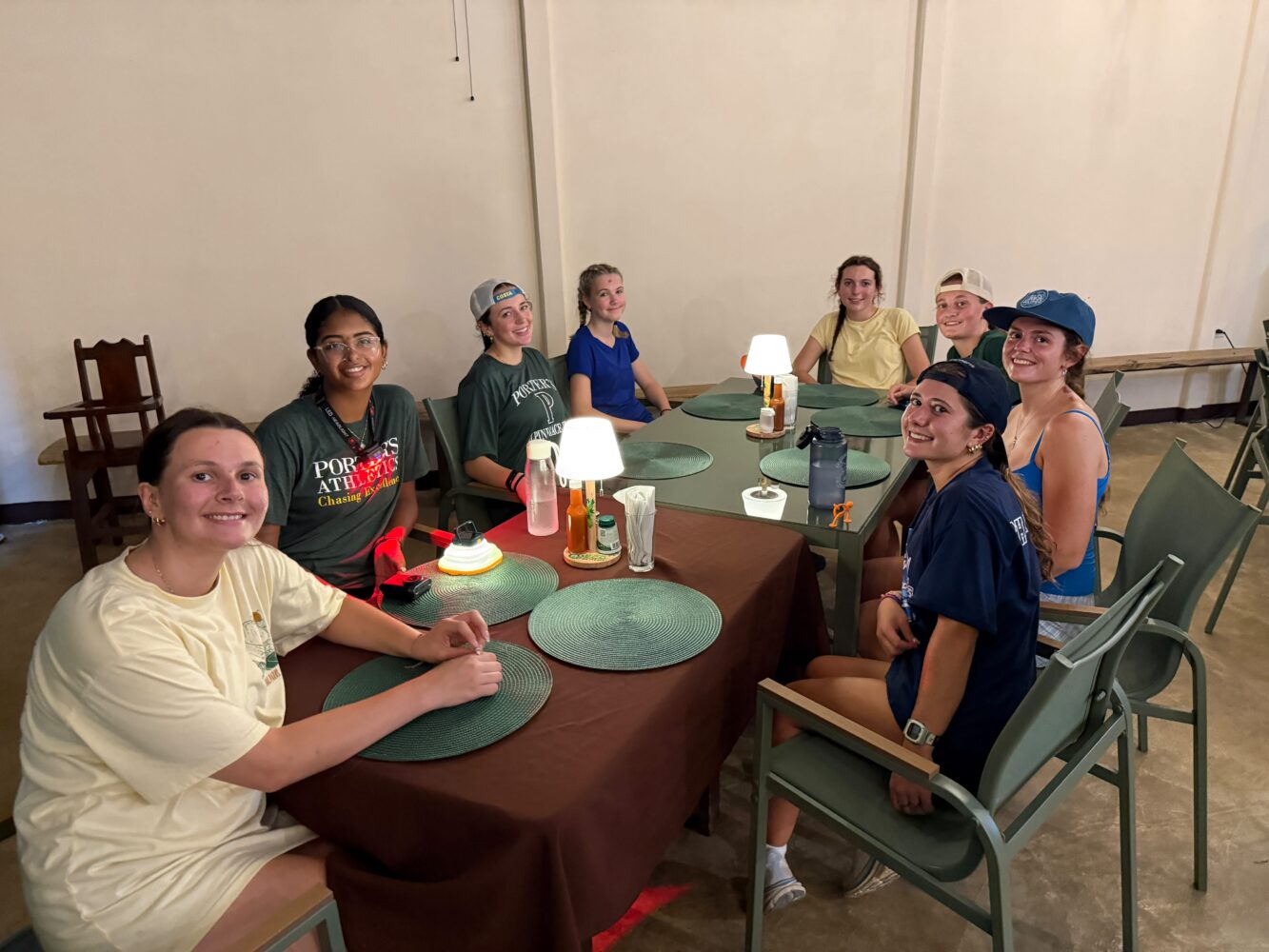 Eight young women sit around a table at a restaurant, smiling for a group photo.